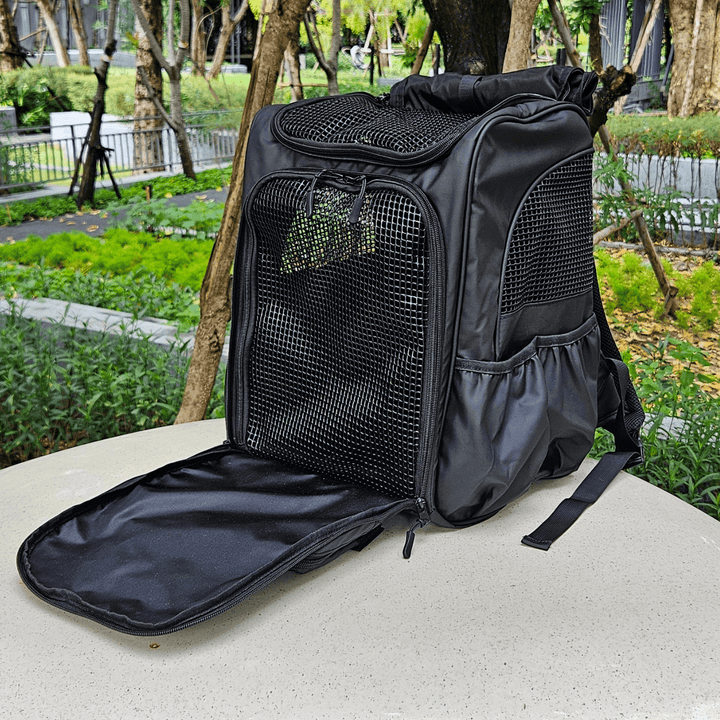 Black outdoor pet backpack with front mesh panel unzipped, showcasing breathable design and spacious interior. Ideal for secure and comfortable pet travel, surrounded by greenery.