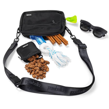 The Pawbella Crossbody Dog Walking Bag, paired with treats, chew sticks, a rope toy, water bottle, waste bags, and black sunglasses—your compact and stylish alternative to bulky pet backpacks in Australia.