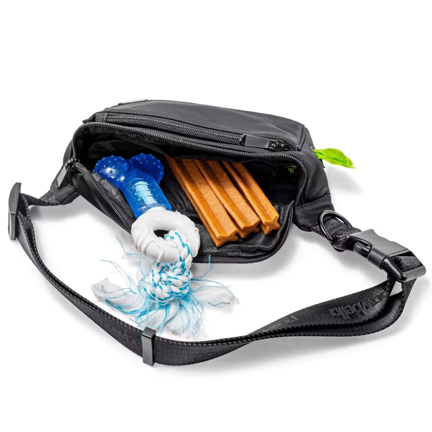 A Pawbella Dog Walking Bum Bag in black is unzipped to reveal a blue dog toy with white rope and three brown chew sticks inside, all shown on a white background.