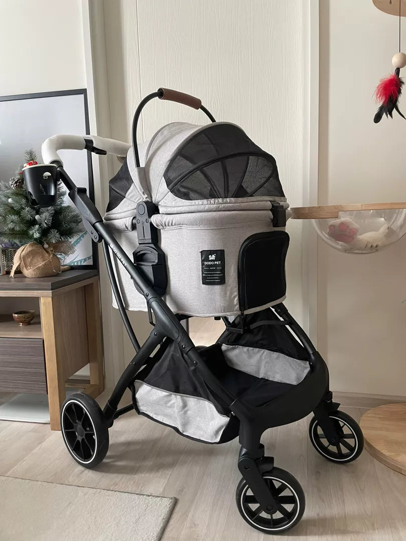 Modern grey pet stroller displayed indoors, featuring a mesh canopy and stylish leather accents on the handle, with a cozy home environment in the background.