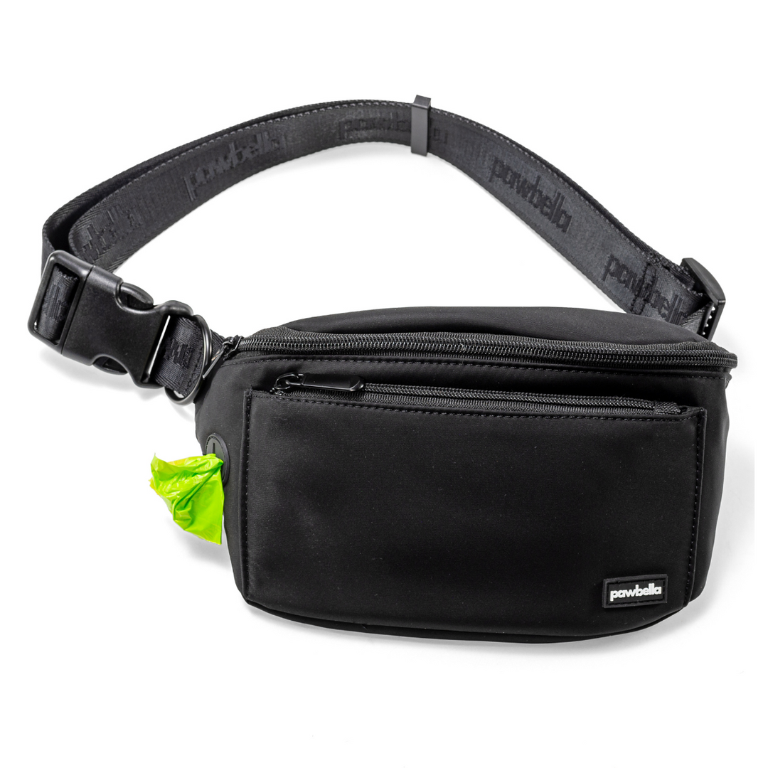 Pawbella dog walking bum bag in black with an adjustable strap, zippered compartments, and a built-in waste bag dispenser with a green bag ready for use.