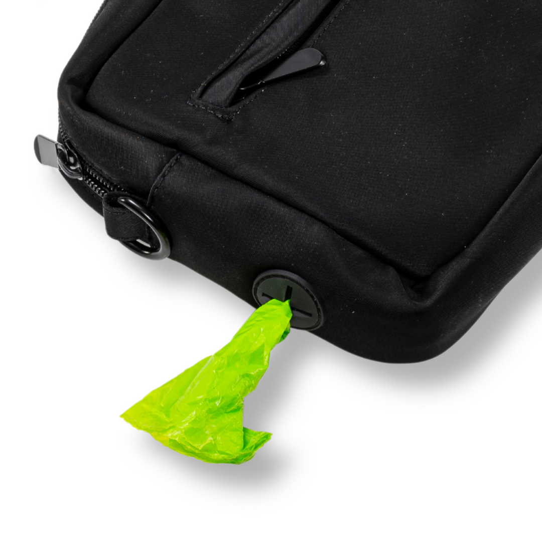 Close-up of the Pawbella dog walking shoulder bag featuring a built-in waste bag dispenser with a green bag inserted for easy cleanup during walks