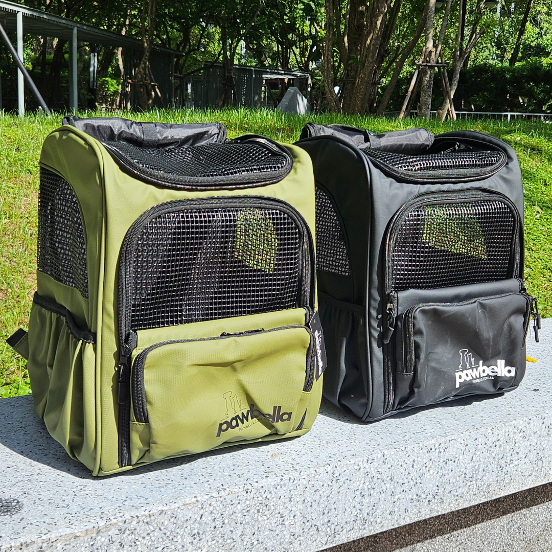 Open Pawbella pet backpacks in olive and black, featuring mesh designs, displayed on a park bench with trees in the background.