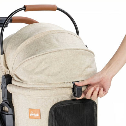 Close-up of a hand unlatching the secure quick-release buckle on the front of the beige Pawbella pet carrier.